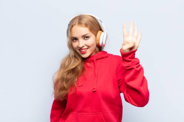 Sarışın kadın gülümsüyor ve arkadaş canlısı görünüyor, 4 ya da 4 numarayı gösteriyor, eli önde, geriye doğru sayıyor.