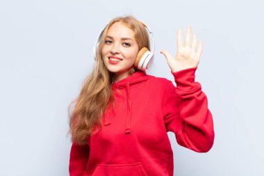 Sarışın kadın gülümsüyor ve arkadaş canlısı görünüyor, 5 ya da 5 numarayı gösteriyor, eli önde, geriye doğru sayıyor.