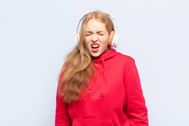 Sarışın kadın agresif bir şekilde bağırıyor, çok kızgın, sinirli, öfkeli ya da sinirli görünüyor.