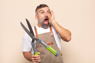 Yetişkin bir adam mutlu, heyecanlı ve şaşırmış hissediyor, iki eli yüzü üzerinde yana bakıyor.