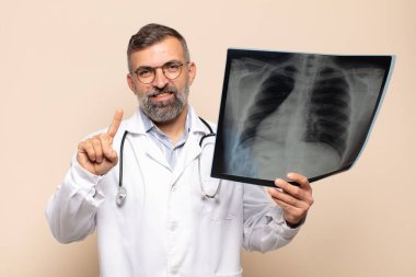 Yetişkin bir adam gülümsüyor ve arkadaş canlısı görünüyor. Bir numarayı gösteriyor ya da ilk eli önde, geri sayıyor.