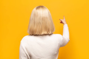 Sarışın kadın dikey görünüm ve fotokopi alanındaki nesneyi işaret ediyor