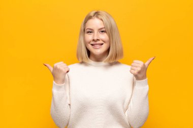 Sarışın kadın neşeyle gülümsüyor ve mutlu görünüyor, kaygısız ve pozitif hissediyor.