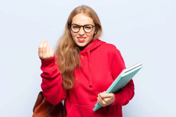 blonde woman making capice or money gesture, telling you to pay your debts!