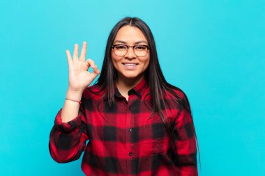 Latin kadın kendini mutlu, rahat ve tatmin olmuş hissediyor. Onayını iyi bir hareketle gösteriyor. Gülümsüyor.