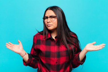 Şaşırmış, kafası karışmış ve stresli görünen Latin bir kadın, farklı seçenekler arasında merak ediyor, kararsız hissediyor.