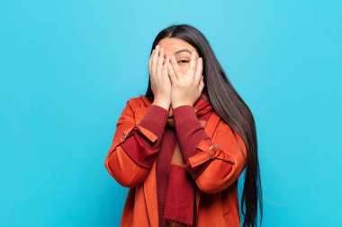 Latin bir kadın korkmuş ya da utanmış hisseder. Gözleri yarı kapalı ya da elleri açık bir şekilde dikizler.