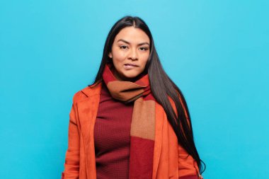 Şaşırmış ve kafası karışmış görünen Latin bir kadın. Sinirli bir hareketle dudağını ısırıyor. Sorunun cevabını bilmiyor.