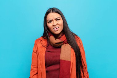 latin woman feeling puzzled and confused, with a dumb, stunned expression looking at something unexpected