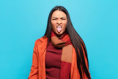 Latin bir kadın tiksinmiş ve rahatsız olmuş hissediyor. Dilini dışarı çıkarıyor. Çirkin ve iğrenç bir şeyden hoşlanmıyor.