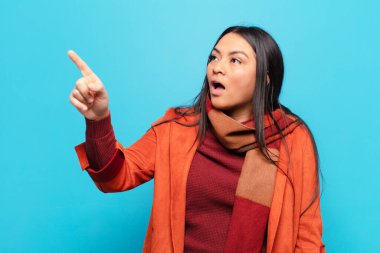 Latin kadın şaşkın ve şaşırmış hissediyor, hayranlıkla yukarı bakıyor, şaşırmış, ağzı açık bakıyor.