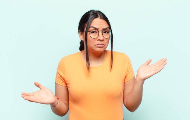 Şaşırmış, kafası karışmış ve stresli görünen Latin bir kadın, farklı seçenekler arasında merak ediyor, kararsız hissediyor.