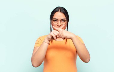 Ciddi ve hoşnutsuz görünen Latin bir kadın reddedilmek için iki parmağını öne uzatmış, sessizlik istiyor.