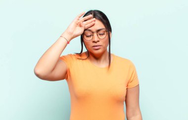 Stresli, yorgun ve hayal kırıklığına uğramış görünen, alnından ter damlayan, umutsuz ve bitkin hisseden Latin bir kadın.