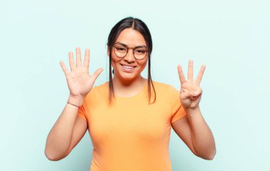 Latin kadın gülümsüyor ve arkadaş canlısı görünüyor, 8 ya da 8 numarayı gösteriyor, elleri önde, geri sayıyor.