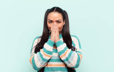 Latin kadın mutlu ve heyecanlı, şaşırmış ve şaşırmış elleri ağızda, tatlı bir ifadeyle kıkırdıyor.