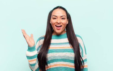 Latin kadın kendini mutlu, şaşırmış ve neşeli hissediyor. Olumlu bir tavırla gülümsüyor. Bir çözüm ya da fikir buluyor.