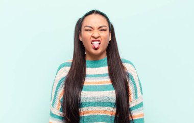 Latin bir kadın tiksinmiş ve rahatsız olmuş hissediyor. Dilini dışarı çıkarıyor. Çirkin ve iğrenç bir şeyden hoşlanmıyor.