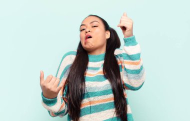 latin woman shrugging with a dumb, crazy, confused, puzzled expression, feeling annoyed and clueless