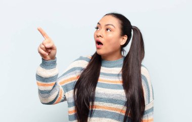 Latin kadın şaşkın ve şaşırmış hissediyor, hayranlıkla yukarı bakıyor, şaşırmış, ağzı açık bakıyor.