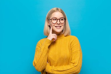 Sarışın kadın mutlu bir şekilde gülümsüyor ve hayal kuruyor ya da şüphe ediyor.