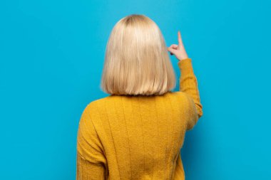 Sarışın kadın dikey görünüm ve fotokopi alanındaki nesneyi işaret ediyor