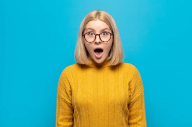 Sarışın kadın çok şaşırmış ya da şaşkın bakıyor, ağzı açık bir şekilde 