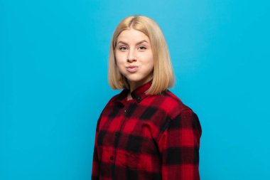 Aptal, çılgın, şaşırmış bir yüzü olan, yanakları şişen, doldurulmuş, şişman ve yemekle dolu bir sarışın kadın.