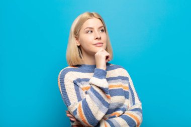 Sarışın kadın düşünceli, meraklı ya da hayal kuruyor, hayal kuruyor ve mekanı kopyalamak için yukarı bakıyor.