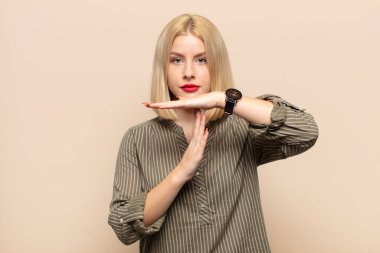 Sarışın kadın ciddi, sert, kızgın ve hoşnutsuz görünüyor.