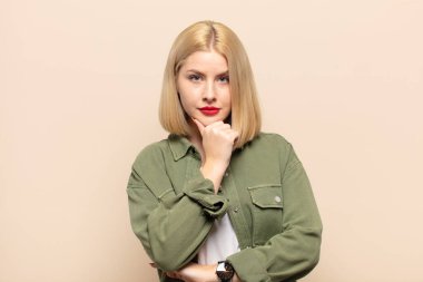 Sarışın kadın ciddi görünüyor, kafası karışık, kararsız ve düşünceli, seçenekler ve seçenekler arasında şüpheci.