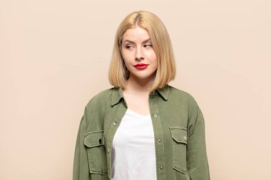 Sarışın kadın merak ediyor, mutlu düşünceler ve fikirler düşünüyor, hayal kuruyor, kenarda yer arıyor.