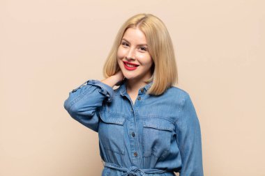 Sarışın kadın neşeli ve kendinden emin bir şekilde gülüyor. Sıradan, mutlu, samimi bir gülümsemeyle.