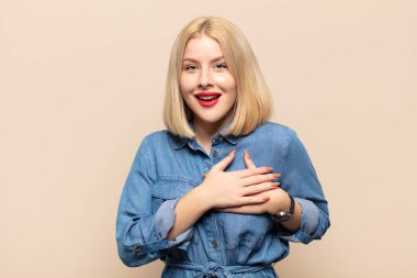 Sarışın kadın romantik, mutlu ve aşık, neşeyle gülümseyen ve kalbe yakın el ele tutuşan