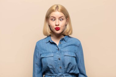 Sarışın kadın aptal ve komik görünüyor. Şaşı bakışlı, şakacı ve şakacı.