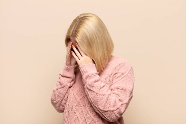 Üzüntülü, hayal kırıklığına uğramış bir bakışla gözlerini kapatan, ağlayan, yan gözle bakan sarışın kadın.