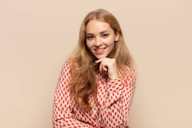 Sarışın kadın mutlu görünüyor ve gülümsüyor. El pençe divan, merak ediyor ya da soru soruyor. Seçenekleri karşılaştırıyor.