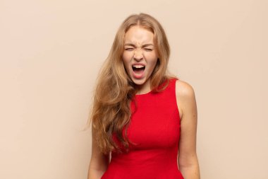 Sarışın kadın agresif bir şekilde bağırıyor, çok kızgın, sinirli, öfkeli ya da sinirli görünüyor.