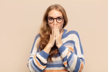 Sarışın kadın endişeli, üzgün ve korkmuş hissediyor. Ağzını ellerle kapatıyor. Endişeli ve berbat görünüyor.