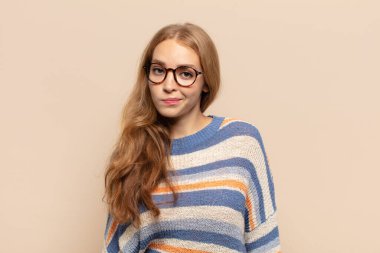 Sarışın kadın şaşkın ve şüpheli hissediyor, merak ediyor ya da karar vermeye çalışıyor.