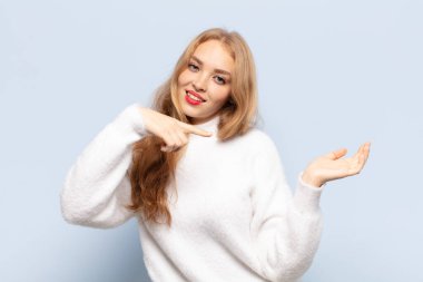 Sarışın kadın gülümsüyor, mutlu, kaygısız ve tatmin olmuş hissediyor, fotokopi alanındaki konsepte ya da fikre işaret ediyor.