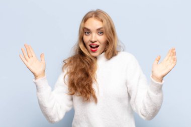 Sarışın kadın mutlu, heyecanlı, şaşırmış ya da şaşırmış hissediyor. İnanılmaz bir şeye gülümsüyor ve şaşırıyor.