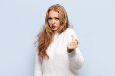 Sarışın kadın kızgın, sinirli, isyankar ve agresif hissediyor, orta parmağını sallıyor, karşı koyuyor.