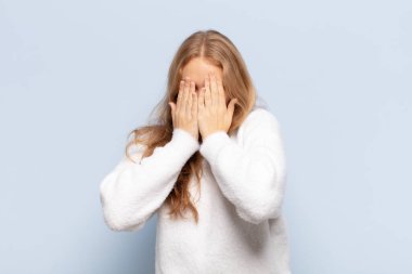 Sarışın kadın üzgün, hayal kırıklığına uğramış, gergin ve depresif, iki eliyle yüzünü kaplayan, ağlayan