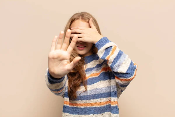 blonde woman covering face with hand and putting other hand up front to stop camera, refusing photos or pictures