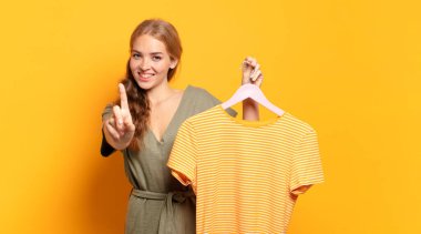 Gururla ve kendinden emin bir şekilde gülümseyerek bir numaralı pozu vererek, bir lider gibi hissederek.