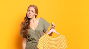 Şaşırmış ve kafası karışmış görünüyor, sinirsel bir hareketle dudağını ısırıyor, sorunun cevabını bilmiyor.