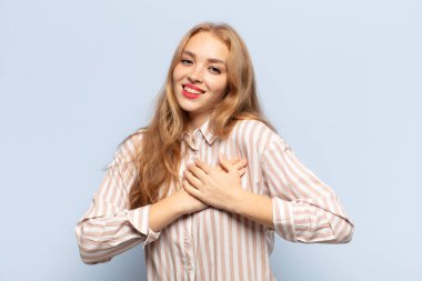 Sarışın kadın romantik, mutlu ve aşık, neşeyle gülümseyen ve kalbe yakın el ele tutuşan