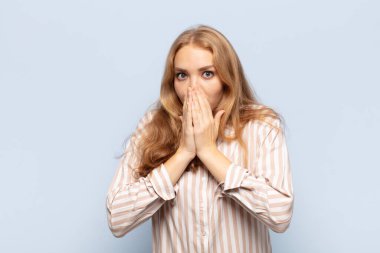 Sarışın kadın endişeli, üzgün ve korkmuş hissediyor. Ağzını ellerle kapatıyor. Endişeli ve berbat görünüyor.