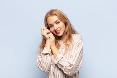 Sarışın bir kadın aşık ve sevimli görünüyor. Sevimli ve mutlu. Romantik bir şekilde gülümsüyor.